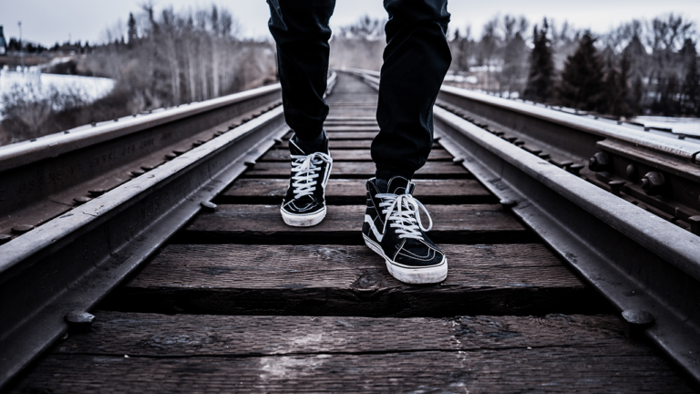 A closeup of a man walking on a train track.