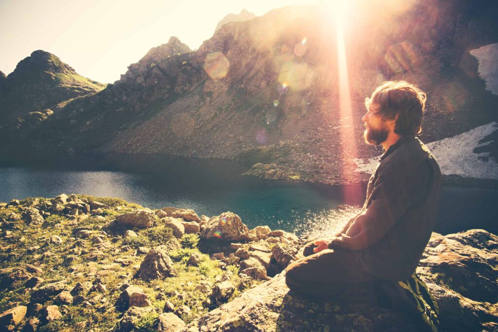 Bearded Man meditating relaxing alone Travel healthy Lifestyle concept lake and mountains sunny landscape on background outdoor