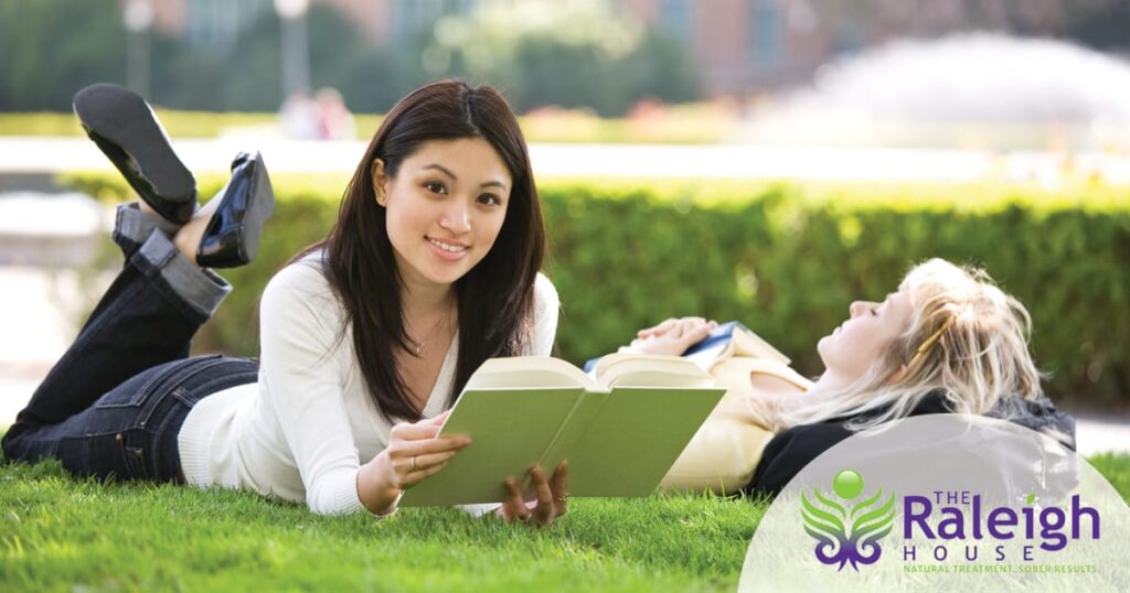 Two female college students take a break on campus on a warm, sunny day.