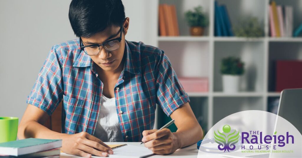 A college student sits at his desk, working on a paper.