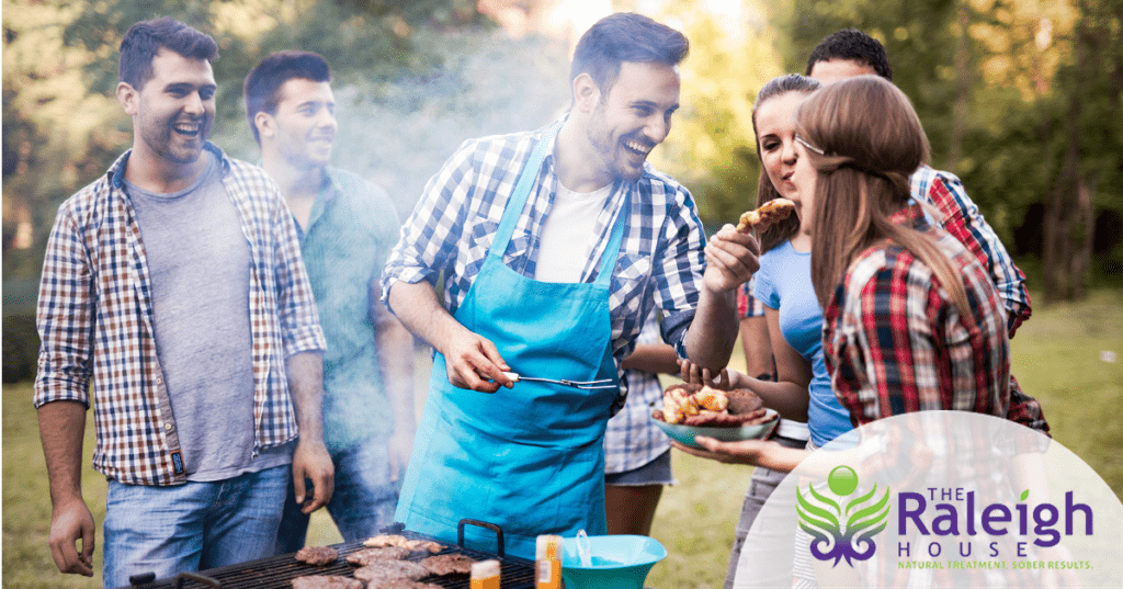 A group of six young adults gathers around a grill at a cookout.