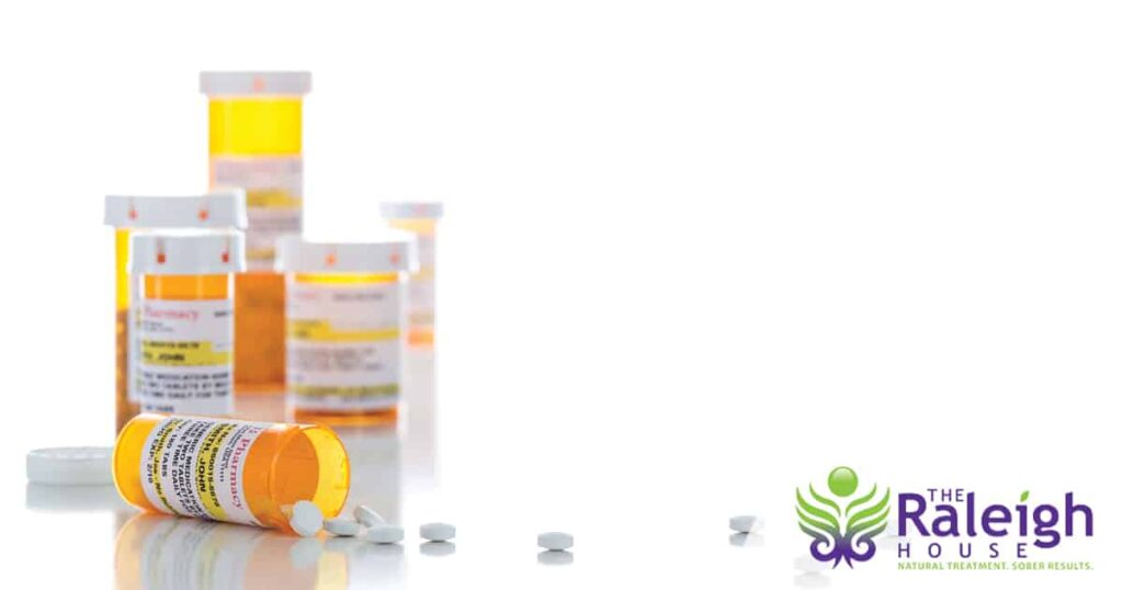 A group of prescription pill bottles containing painkillers sits on a counter.