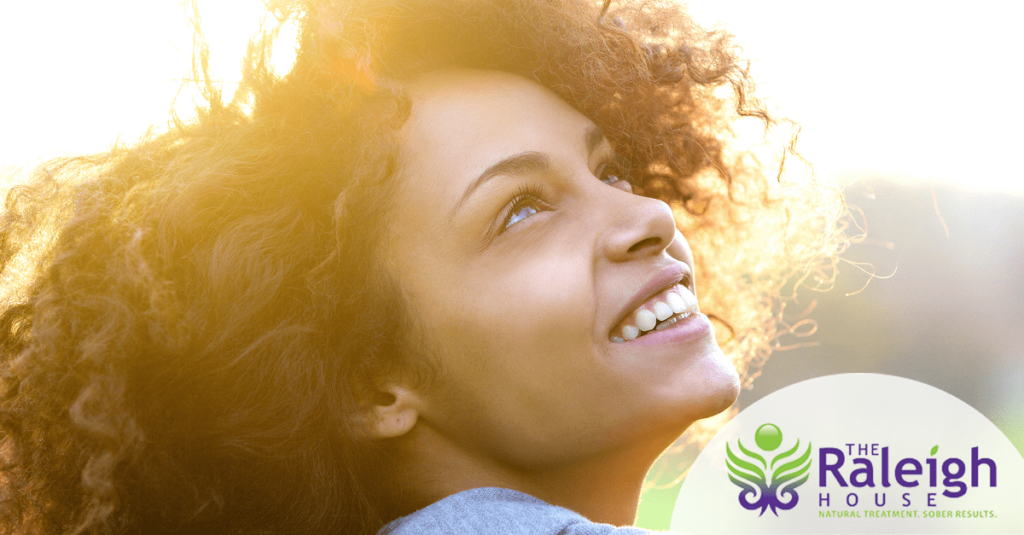 A young woman tilts her smiling face up to the sun.