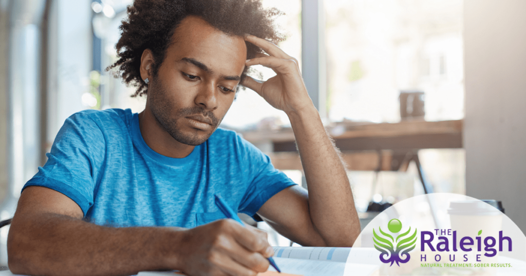 A man deep in thought works on schoolwork in a cafe.
