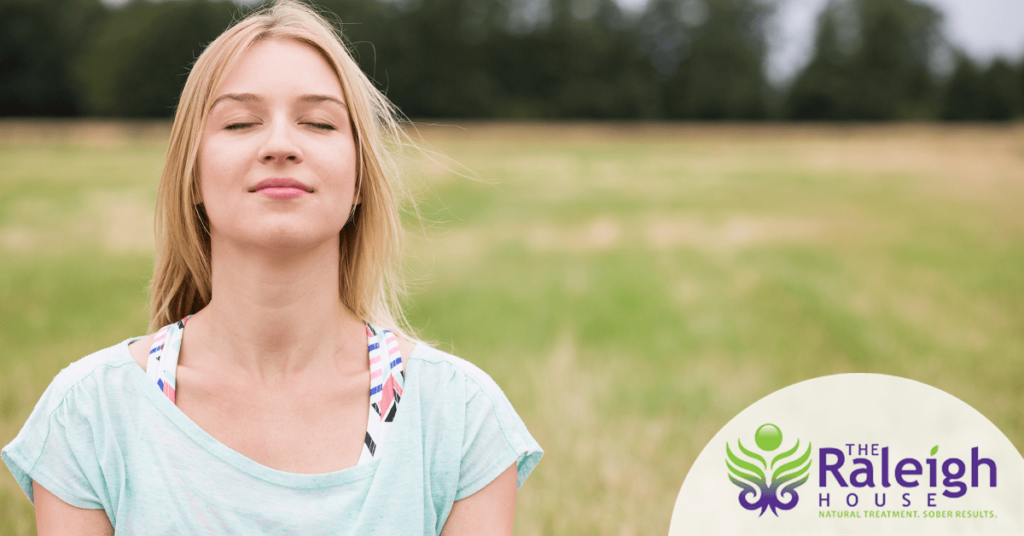 A woman practices meditation in a peaceful meadow as a means to cope with cocaine addiction recovery and anxiety.