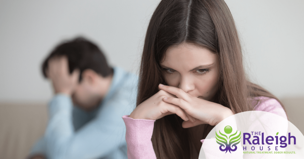 A young couple sits silently together after having an argument.