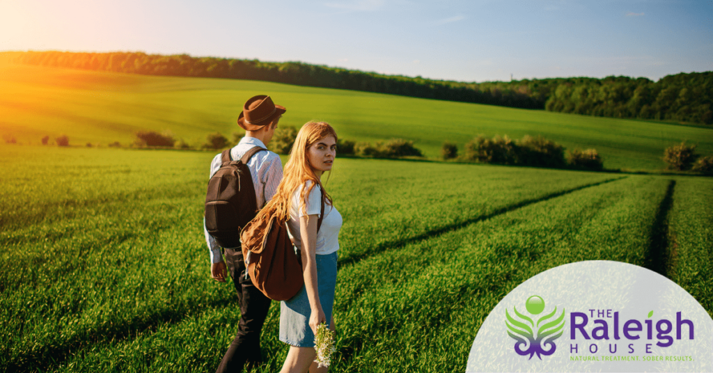 A happy young couple walks through a meadow on a sunny day. 