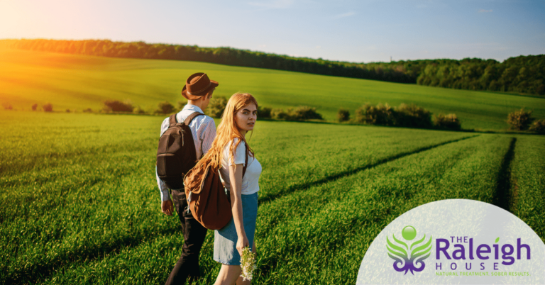 A happy young couple walks through a meadow on a sunny day.