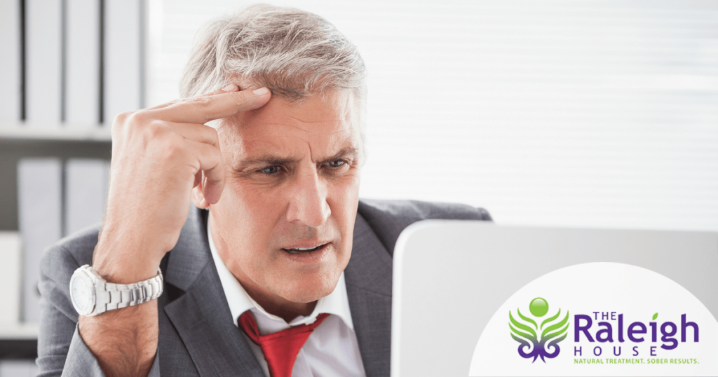 A business man appears confused on his computer in his office.