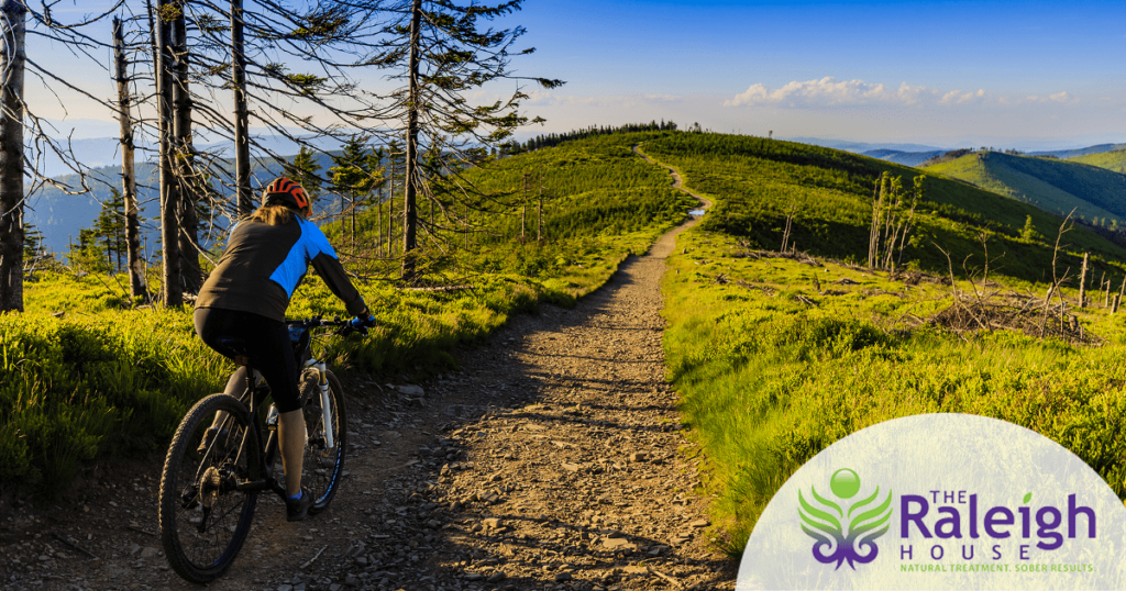 A woman rides her bike down a winding dirt path.
