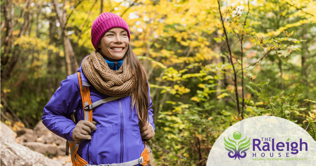 A young woman smiles as she hikes through the woods on a beautiful fall day.