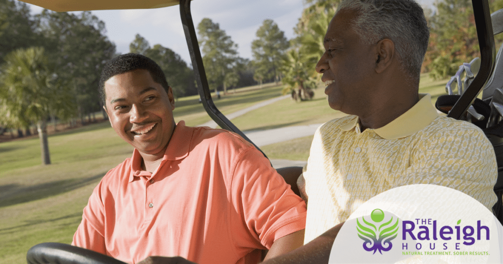 A father and his adult son ride together in a golf cart.