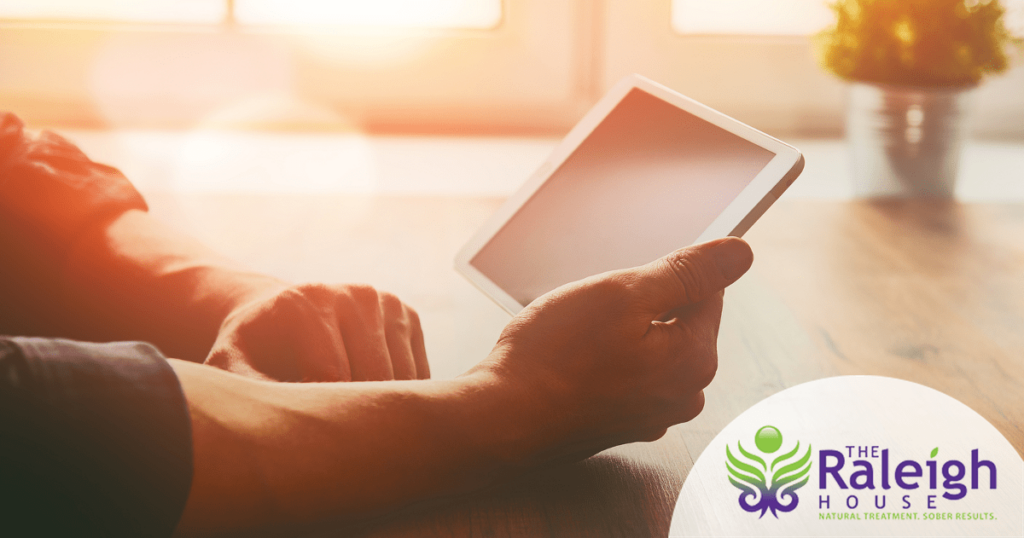 A close-up shot of a man holding a tablet, as sun streams in through the window.