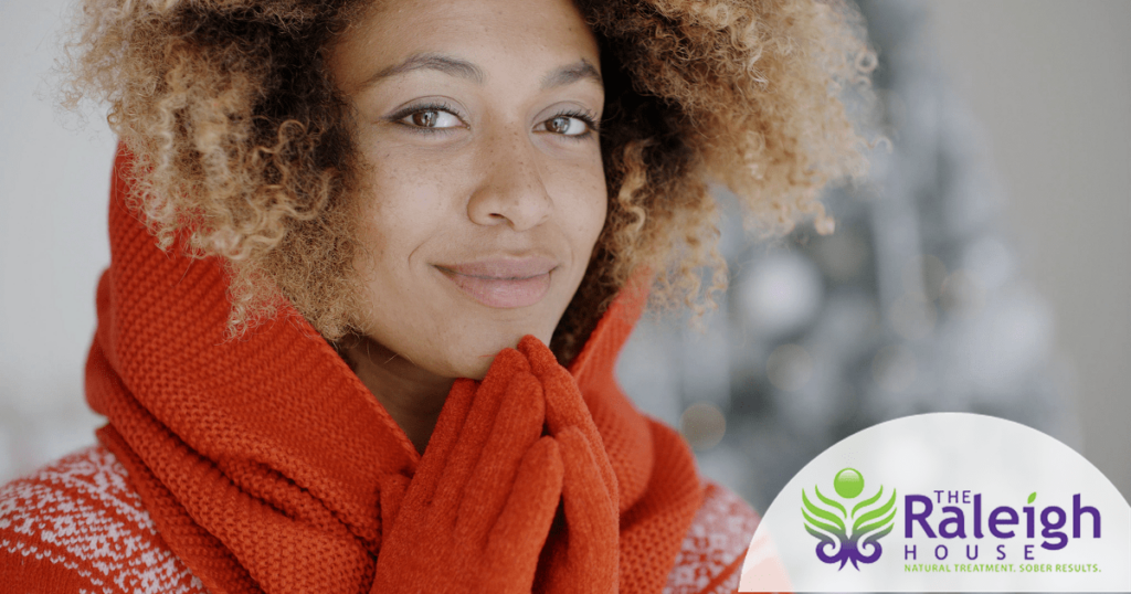 A young woman wearing a festive holiday scarf smiles.