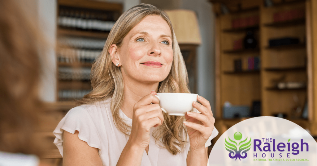 A middle aged woman enjoys a cup of coffee in a a coffee shop.