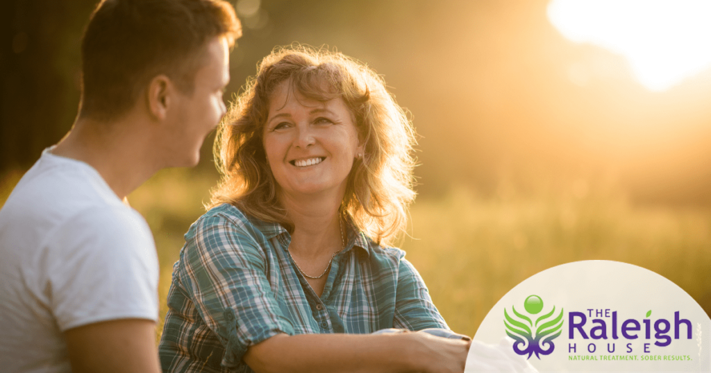 A son and his mother smile as they enjoy the sunset out in nature.