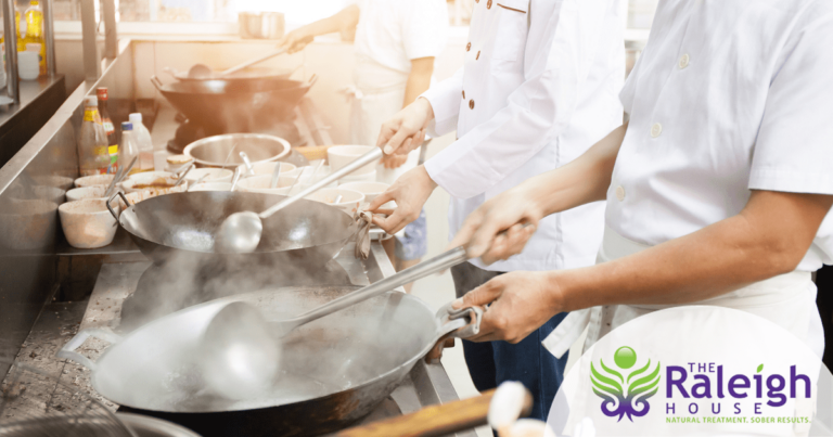 A group of chefs works quickly in a restaurant to prepare entrees.
