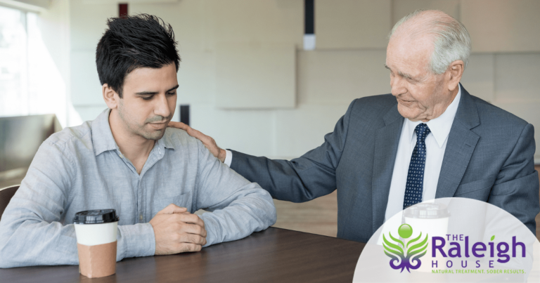 A sad man being comforted by an older gentleman.