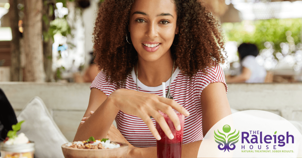 A healthy young woman eats a salad and drinks a smoothie.  