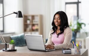 A woman is working from home by herself in a bright, sun-lit room.