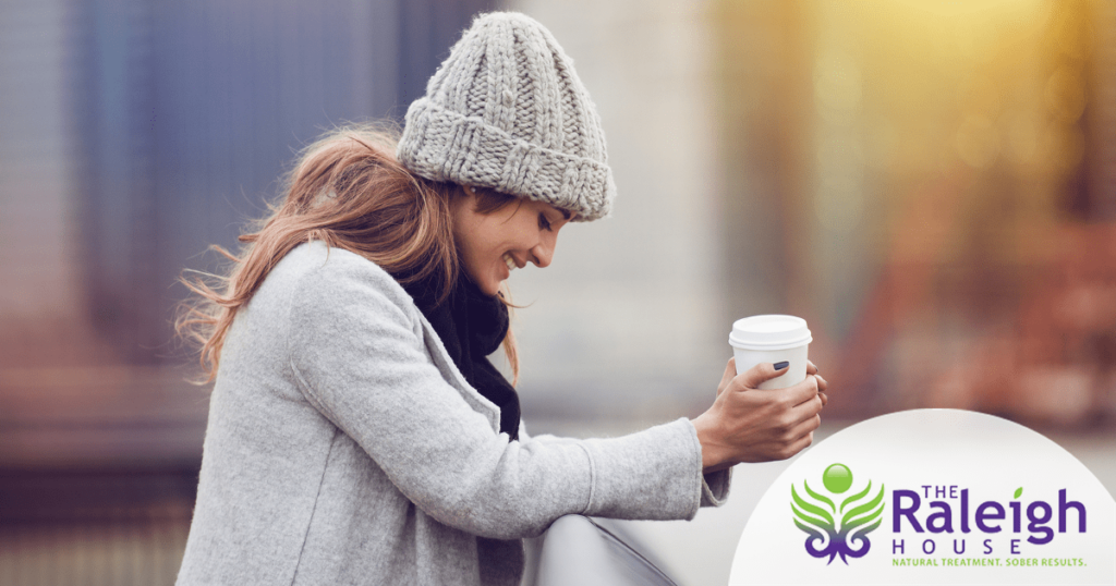 A woman holds a cup of coffee while standing outside in the winter in New York City