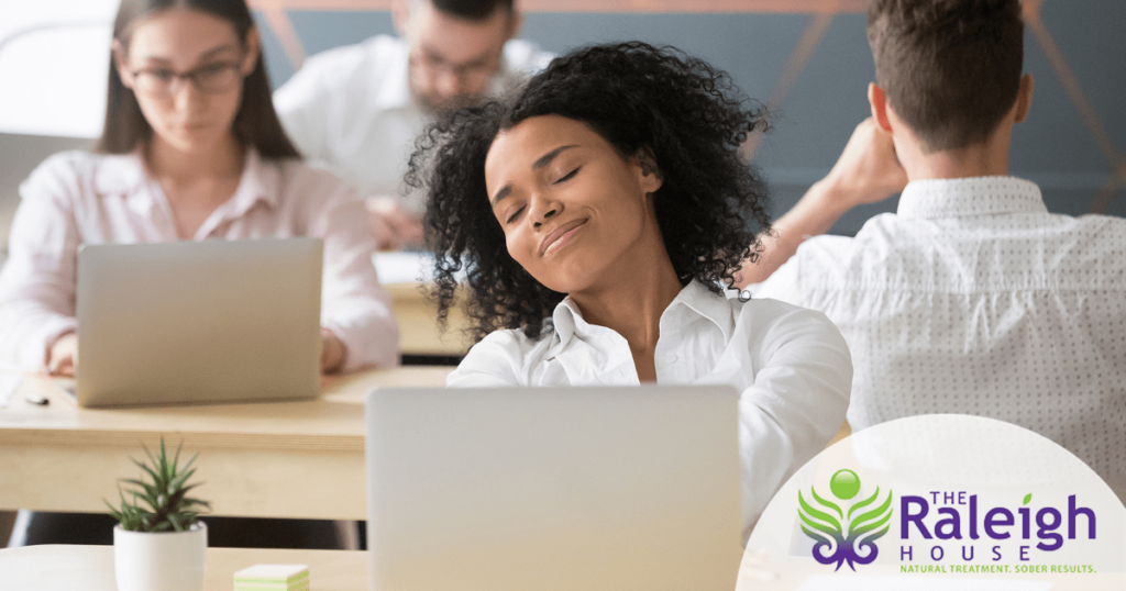 A young woman sits at her desk at work, looking calm and happy.