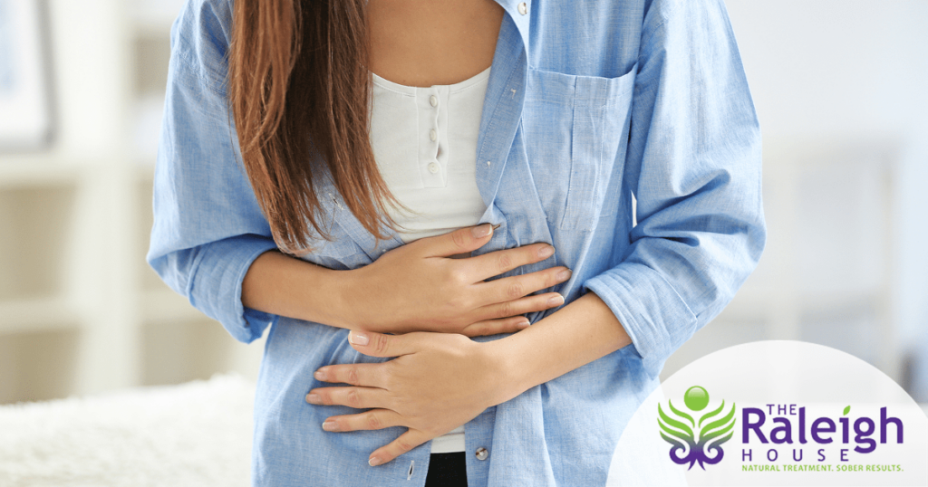 A young woman holds her stomach.