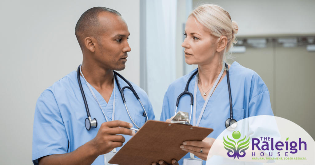 Two nurses stand together looking over a file.