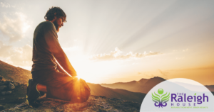 A man sinks to his knees and admires a mountain-top view of the sunset.