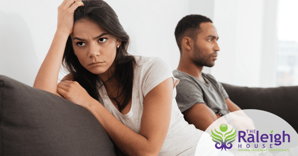 A husband and wife sit angrily on a couch after an argument .