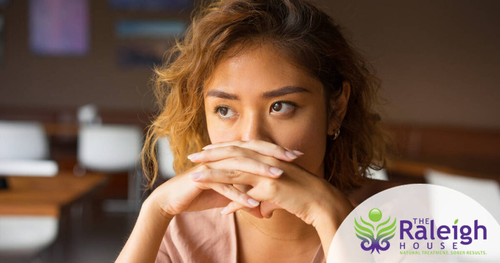 A young woman sits in a café looking distressed.