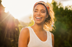 A pretty young woman smiles as the sun shines down on her.
