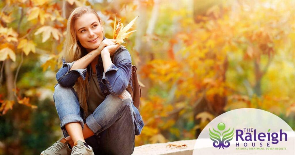 A woman sits in a park enjoying a beautiful fall day.