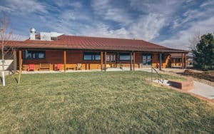 An exterior photo of a large log-cabin inspired ranch home, set on 40 acres near Denver.