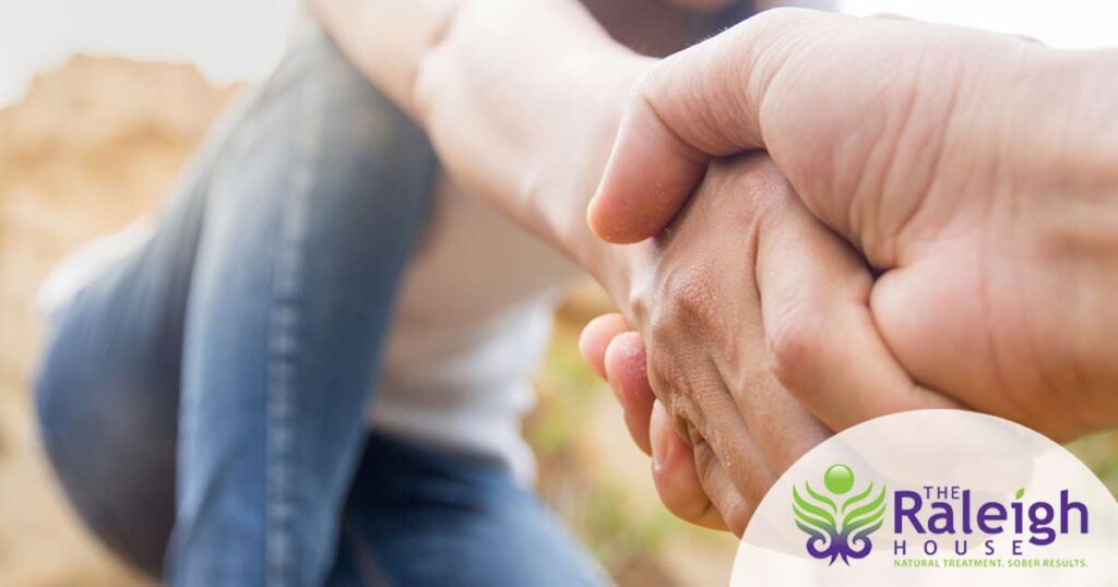 A close-up shot of the hand of someone helping another person up a hill