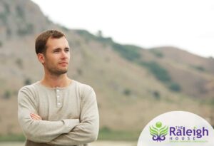 A young man stands in front of a mountain.