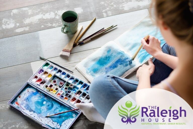 A woman works on an abstract blue painting.