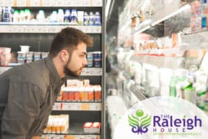 A man in recovery contemplating buying milk and other dairy products from a grocery store.