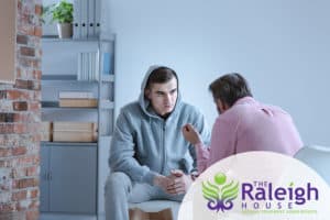 A young man talking to a therapist in outpatient addiction treatment.