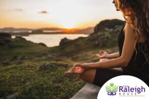 A woman in addiction recovery practicing yoga outdoors.  