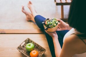 A woman eating healthy fruits and vegetables as part of her pro-recovery diet.