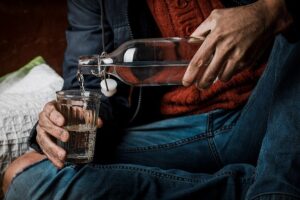 A man drinking liquor and worsening his struggle with alcohol addiction.