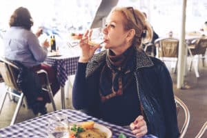 An older woman drinking wine at lunch.