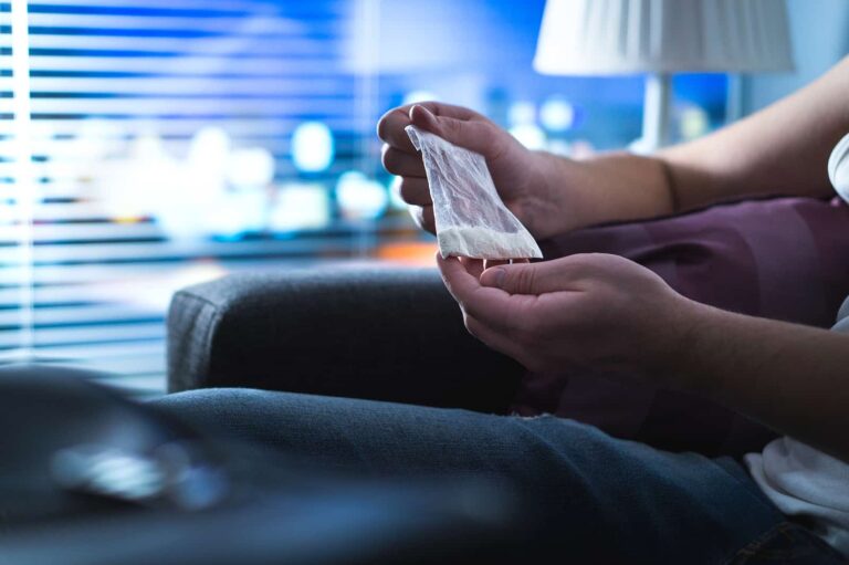 A man holding a bag of crystal meth at home.