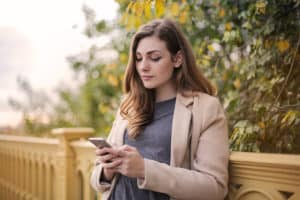 A woman on her phone, receiving peer support in her addiction recovery.