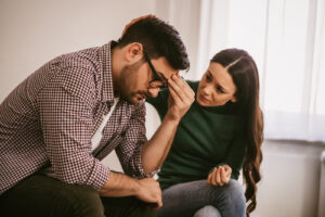 A man struggling with depression and being consoled by his wife.
