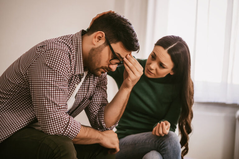 A man struggling with depression and being consoled by his wife.
