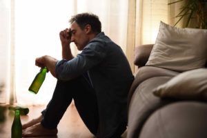 A man sitting at home struggling with alcoholism.