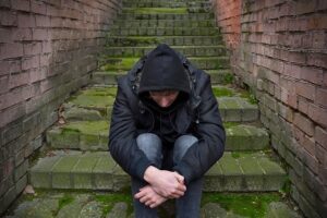 A man struggling with addiction sitting outside.