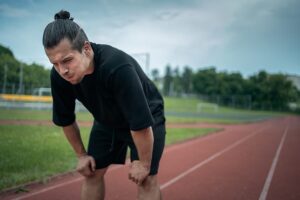 A man hunches over to catch his breath after going on a run.